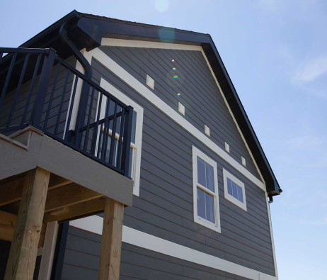 Looking up towards the roofline of a house with neat siding and trim