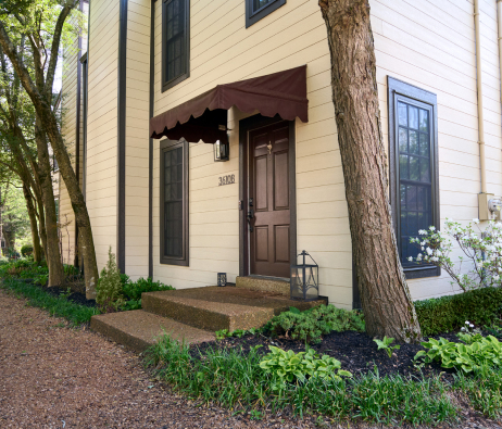 Angled closeup view of the front door of a house with horizontal siding on it