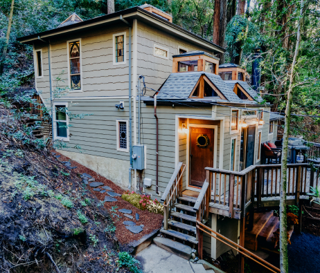 A home with siding nestled in a forested hillside.