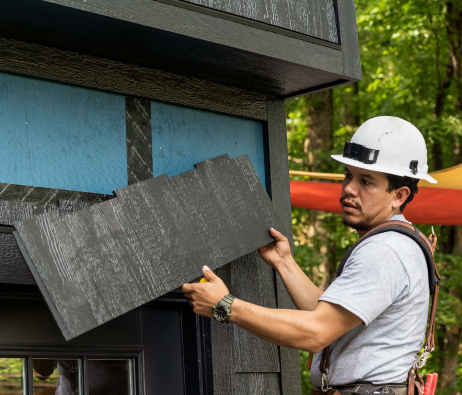 Un trabajador con casco levanta un panel de tejuelas de cedro para ponerlo en su lugar.