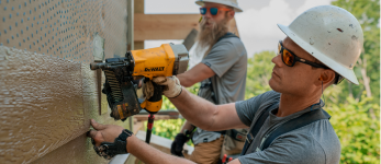 man using nail gun on siding