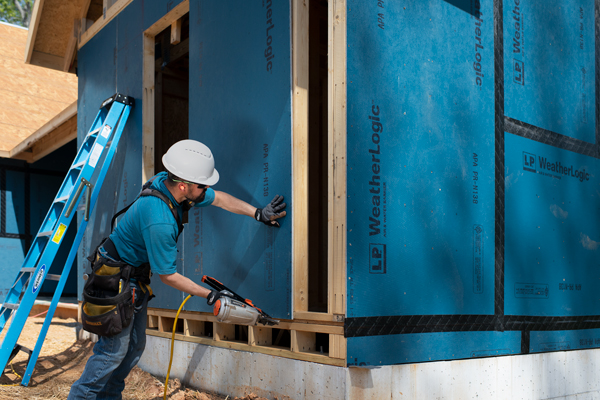 builder with nail gun installing lp weatherlogic sheathing